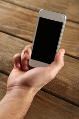 Hand holding smart mobile phone on wooden table background