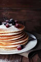 Stack of delicious pancakes with powdered sugar and berries