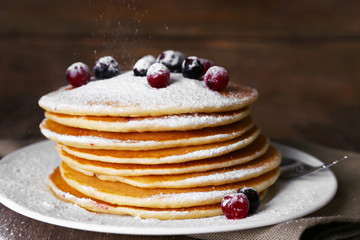 Stack of delicious pancakes with powdered sugar and berries