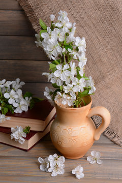 Beautiful fruit blossom in pitcher on table on grey background