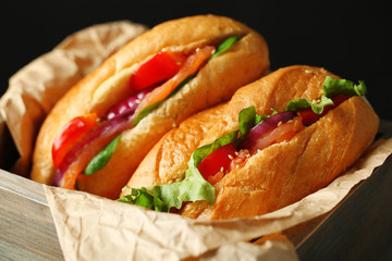 Sandwiches with salmon in wooden box on dark wooden background