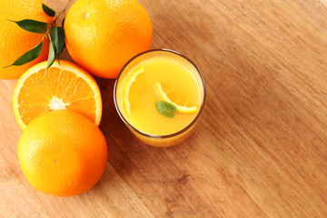Glass of orange juice with slices on wooden table background