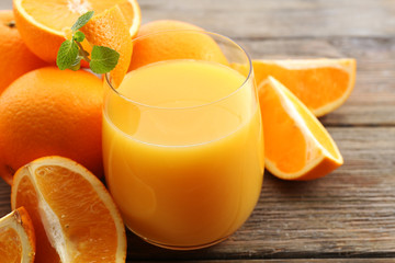 Glass of orange juice and slices on wooden table background