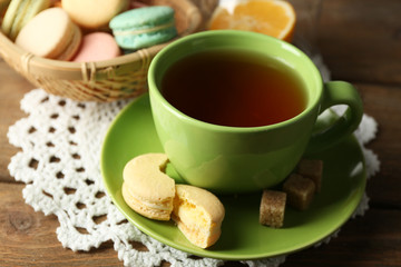 Colorful macaroons with cup of tea on wooden background