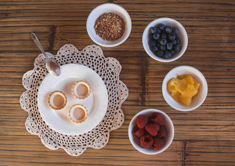Cooking sweet tartlets with raspberry, blueberries, mango and nu