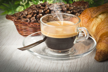 coffee in glass cup with croissants and coffee beans