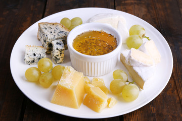 Different sort of cheese with grape and saucer
