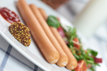 Wiener sausage with ketchup, mustard and salad.