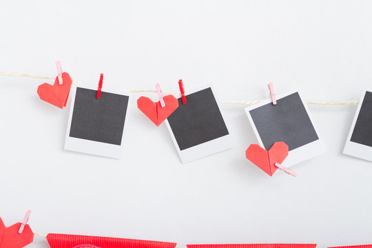 Origami heart and instant photos hanging on clothesline