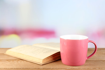 Cup of tea and book on table, on bright background