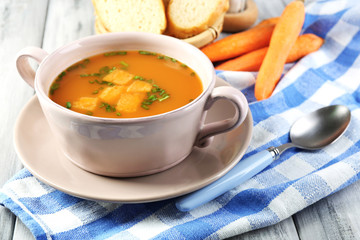 Carrot soup, cream and spoon, on  color wooden background