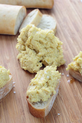 Chickpea and tahini hummus dip on a sliced bun.