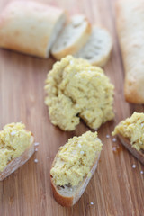 Chickpea and tahini hummus dip on a sliced bun.