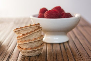 Cooking sweet tartlets with raspberry on wooden table