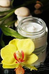 Obraz na płótnie Canvas Face cream with orchid flower on dark background