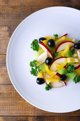 Waldorf salad with olive on plate on wooden background