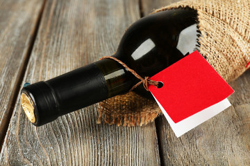 Wine bottle wrapped in burlap cloth on wooden planks background