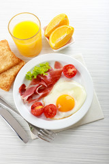 Bacon and eggs on color wooden table background