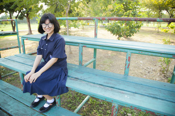 Girl wearing glasses sitting on the bench.