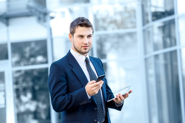 Fototapeta premium Attractive young businessman using a cell phone, smiling. Taken
