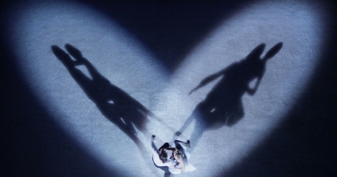 Figure skaters performing love dance in spotlight