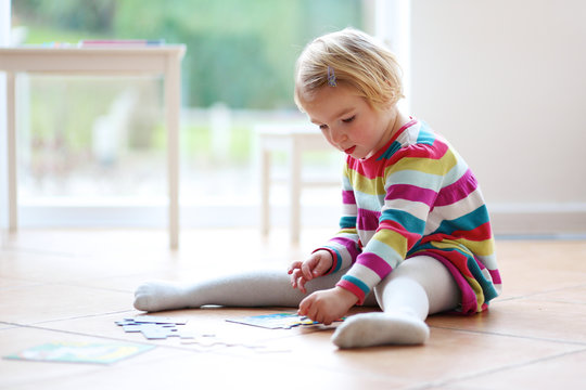 Toddler girl playing on the floor with jigsaw puzzle