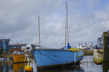 Naklejka premium Blue Boat cloudy sky empty harbor harbour Brixham Devon England