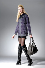 full-length fashion or casual woman holding bag posing studio