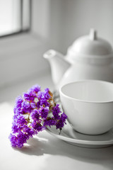 Violet flower beside a white cup