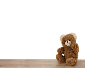Happy Teddy bear sitting and waving on a wooden floor.