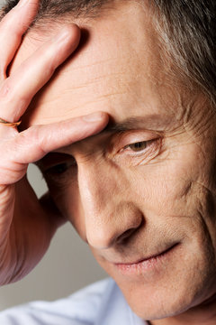 Sad mature man touching his head