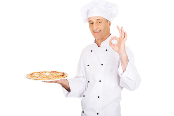 Chef baker with italian pizza showing perfect sign