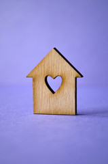 Obraz na płótnie Canvas Wooden house with a hole in the form of heart close-up on a purp