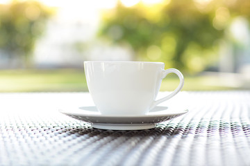 Coffee cup on the table with blurred green nature background 