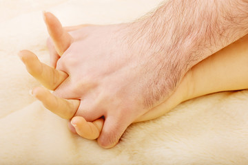 Hands of female and male lying on bed.