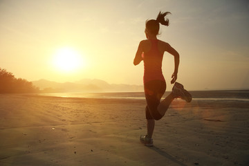 young woman running on sunrise beach
