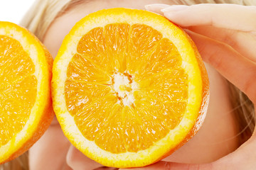 Close up woman holding oranges on eyes