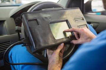 Mechanic using diagnostic tool in the car