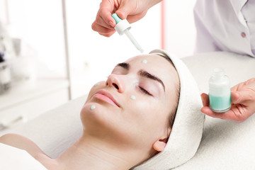 Obraz na płótnie Canvas Serum facial treatment of young woman in spa salon
