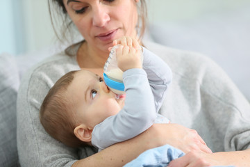 Mother and baby boy holding baby bottle