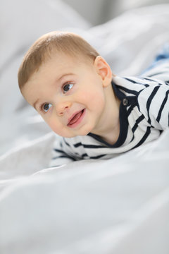 Cheerful baby boy laying over bed
