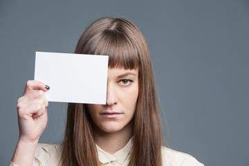 Pretty young girl holding white empty card