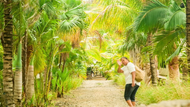 african mixed woman walking down path with palm trees