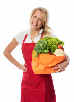 Frau mit Schürze hält frisches Gemüse