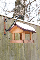 Hanging bird feeder covered by snow in winter.