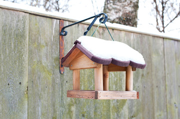 Hanging bird feeder covered by snow in winter.