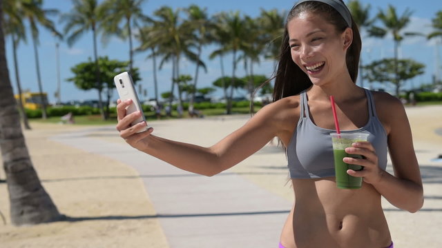 Selfie fitness woman drinking green smoothie