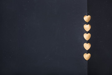 Gold heart stickers on dark texture background with blank space