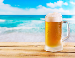 mug of beer on wooden table over sea