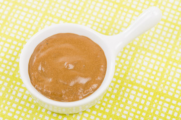 French Mustard - Bowl of french mustard on a green background.